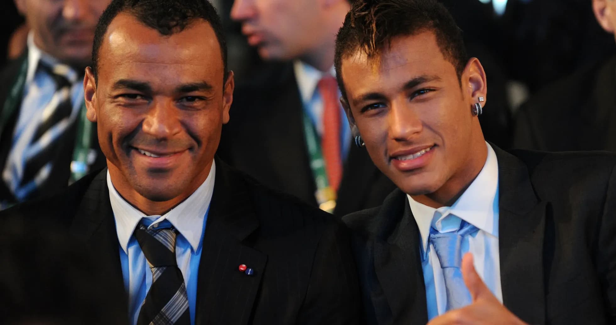 Two men smiling at an event, dressed in suits
