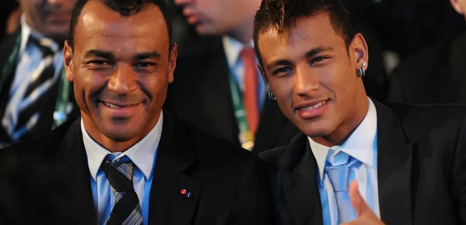 Two men smiling at an event, dressed in suits