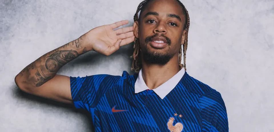 Player in blue France jersey posing with hand raised
