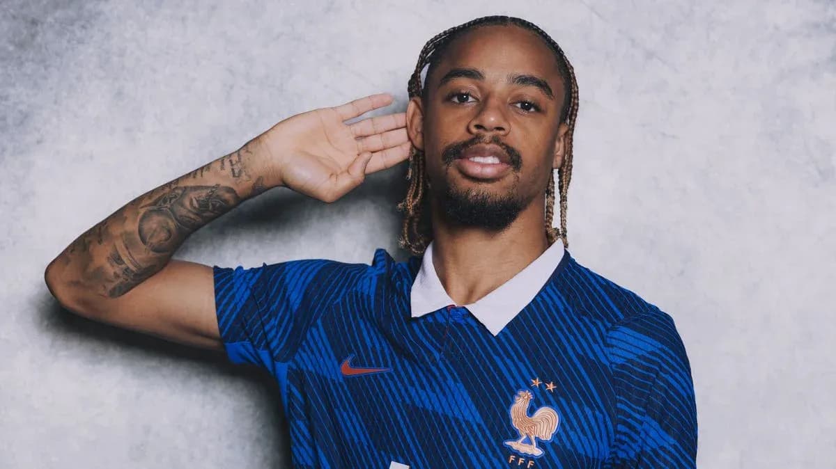 Player in blue France jersey posing with hand raised