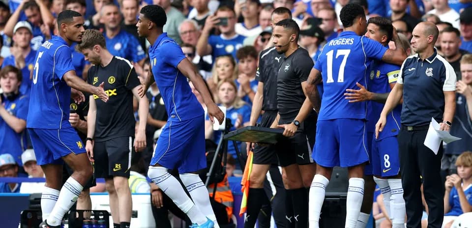 Players exchanging greetings during a substitution on pitch
