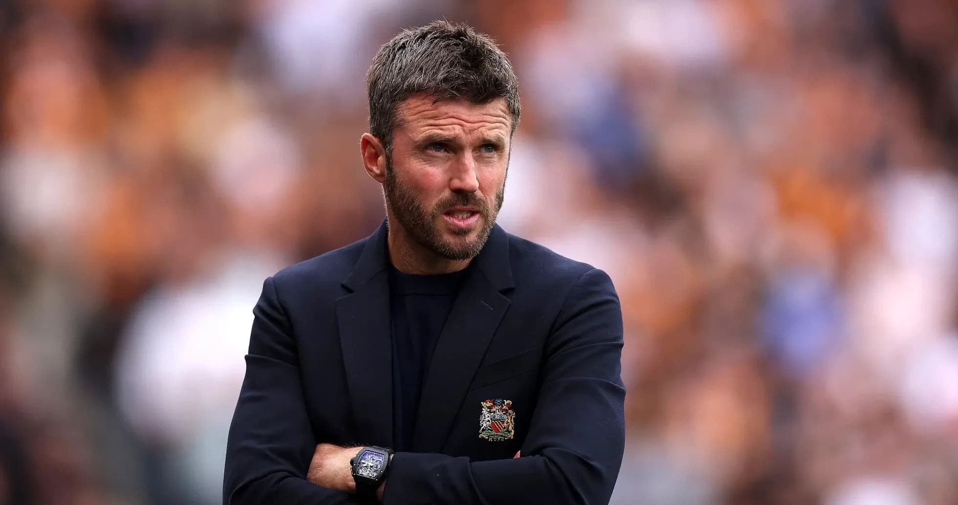 Coach observing match with arms crossed on sidelines