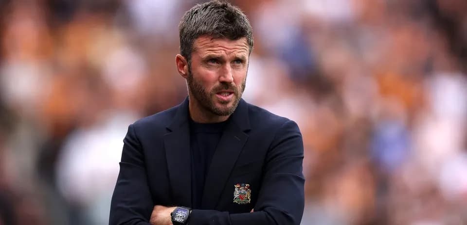 Coach observing match with arms crossed on sidelines