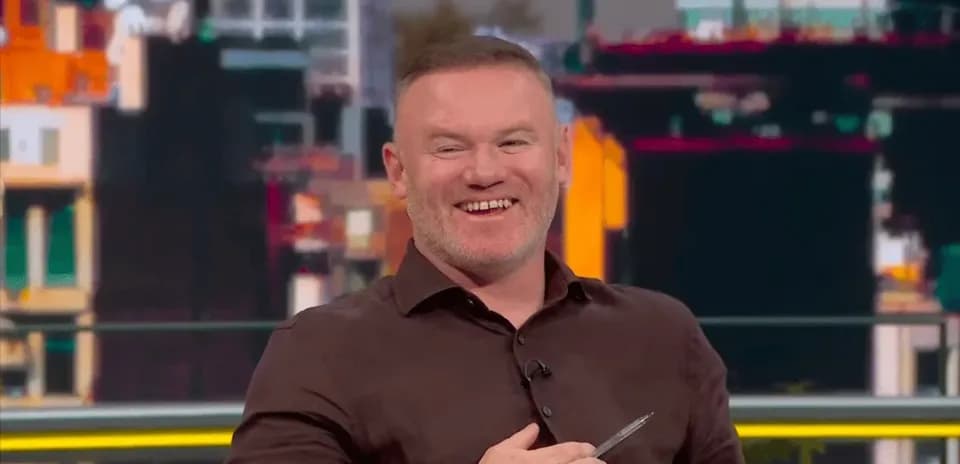 Presenter smiling while holding a pen in studio