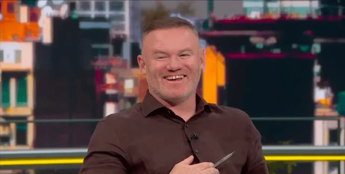 Presenter smiling while holding a pen in studio