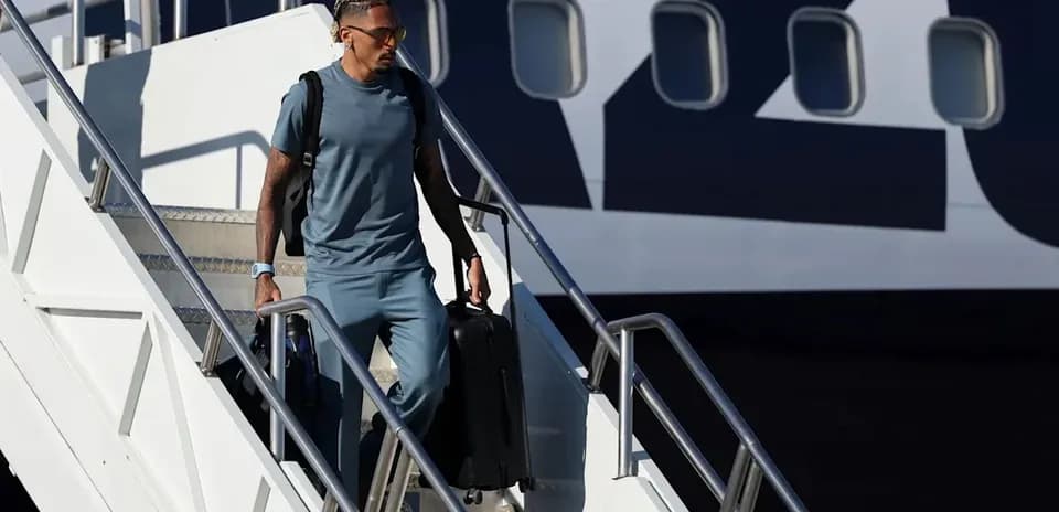 Player exiting airplane with suitcase in hand
