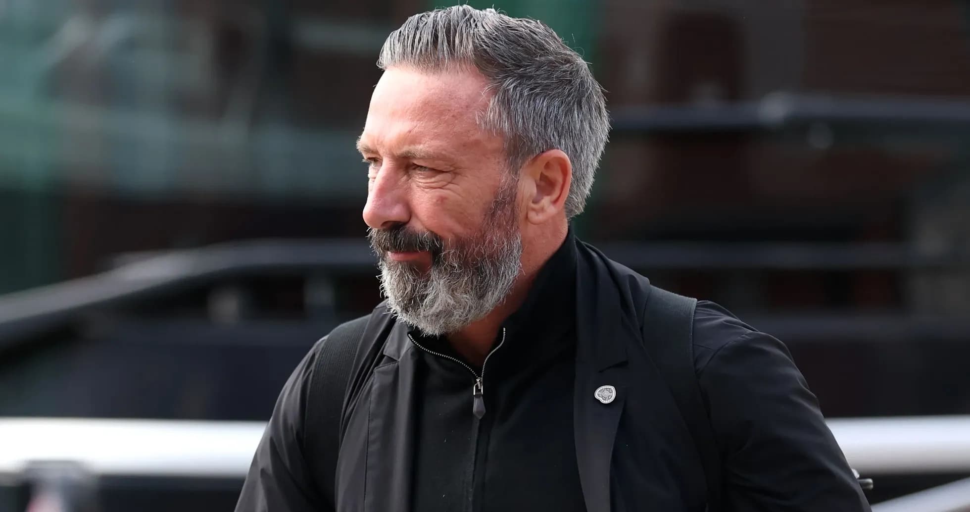 Man with gray beard walking near a bus