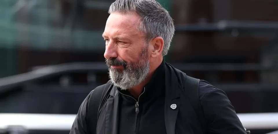 Man with gray beard walking near a bus