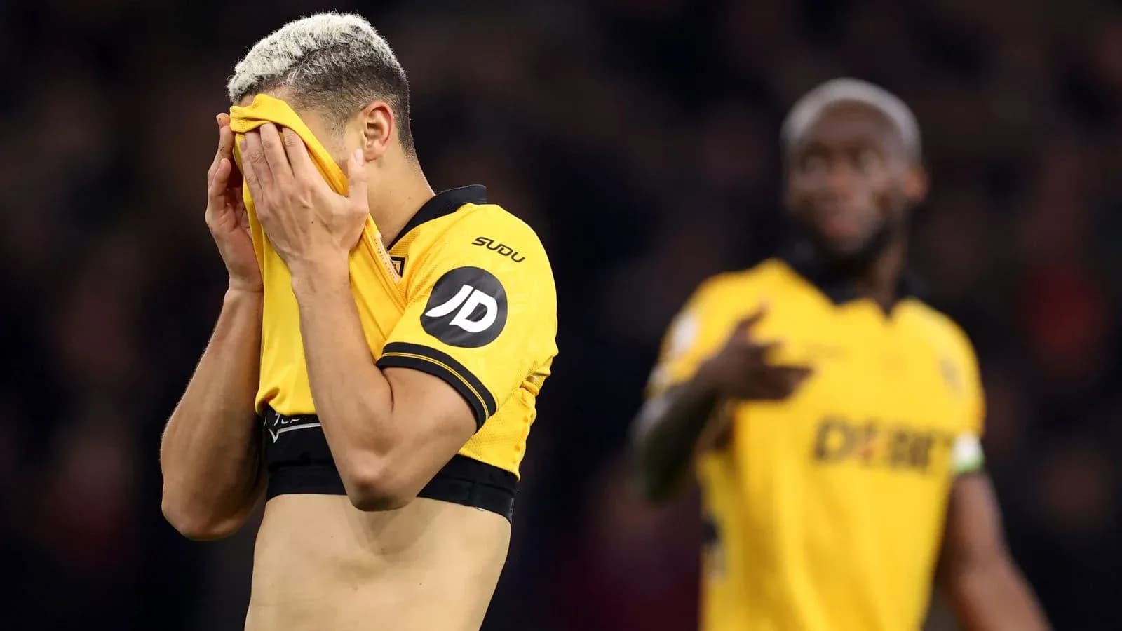 Player covering face with shirt after match