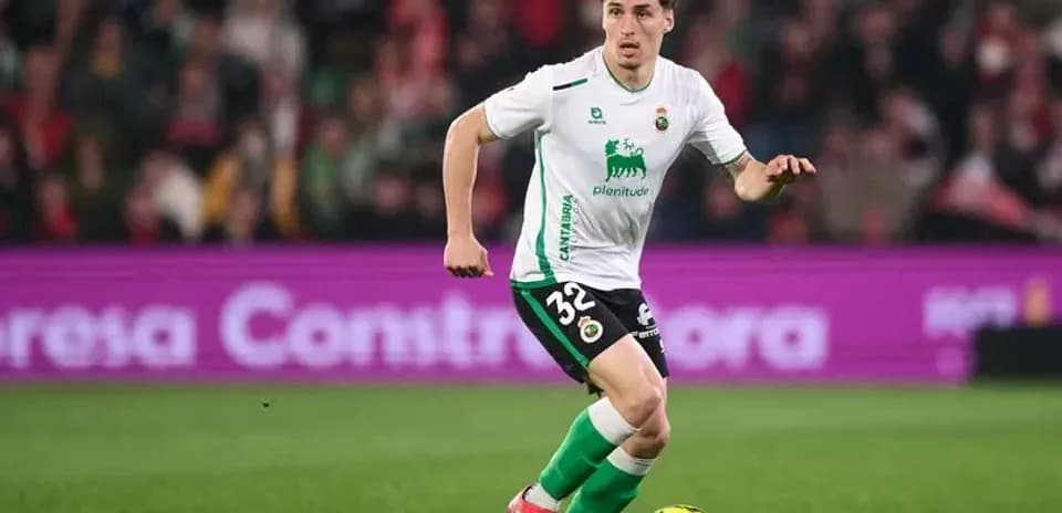 Player in green and white kit dribbling ball on pitch