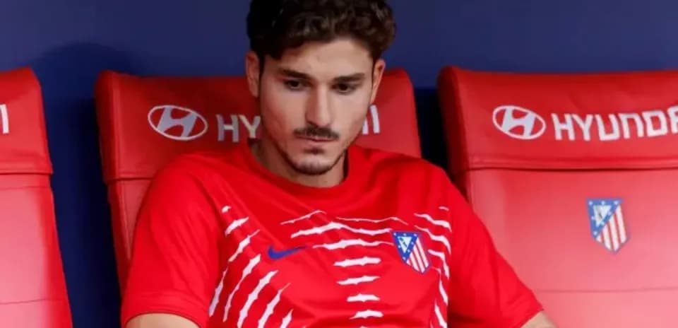 Player sitting on bench wearing Atlético Madrid kit