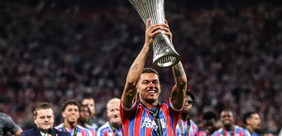 Player celebrating with trophy and teammates in background
