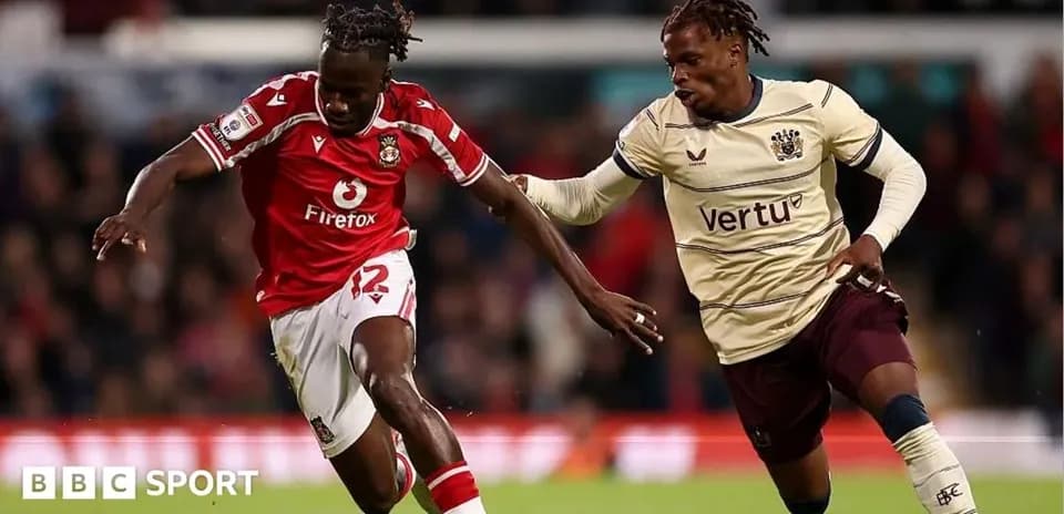 Player in red dribbling past opponent in beige jersey