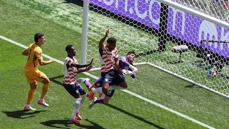 Players contesting near goal during soccer match