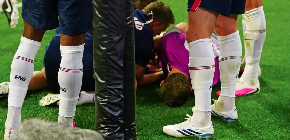 Players surrounding injured teammate on the field