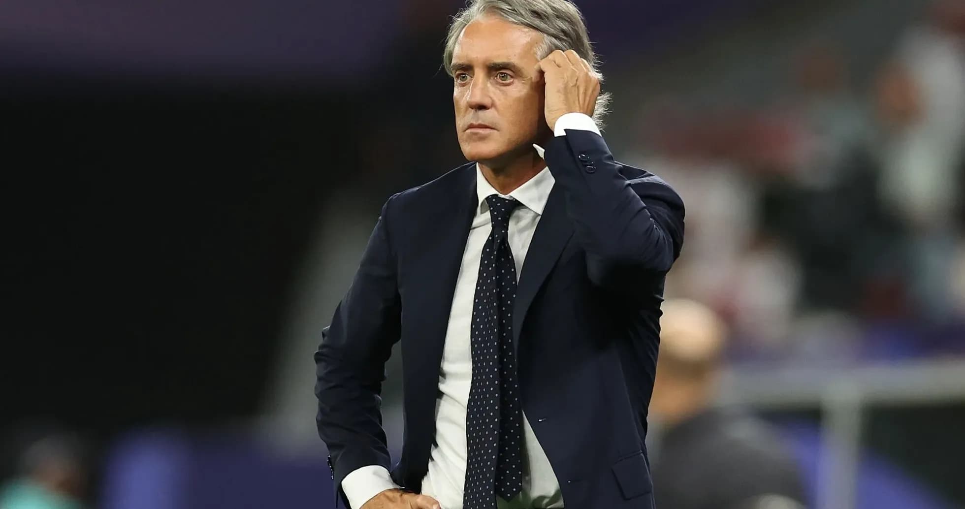Coach observing match from sidelines with hand on head