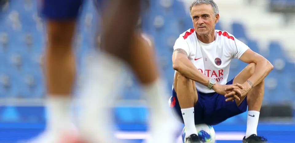 Coach squatting on the pitch during training session