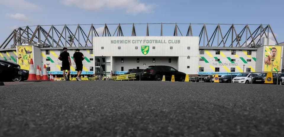 Two people walking towards Norwich City Football Club