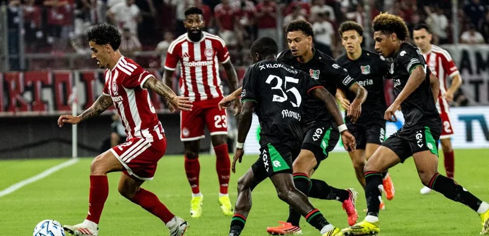 Olympiakos player dribbling past NEC defenders