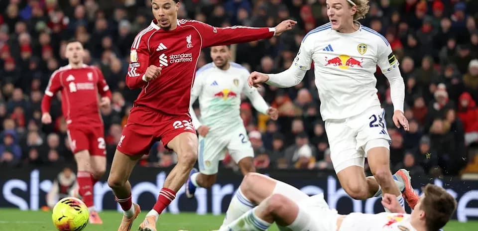 Liverpool player dribbling past Leeds opponents during match