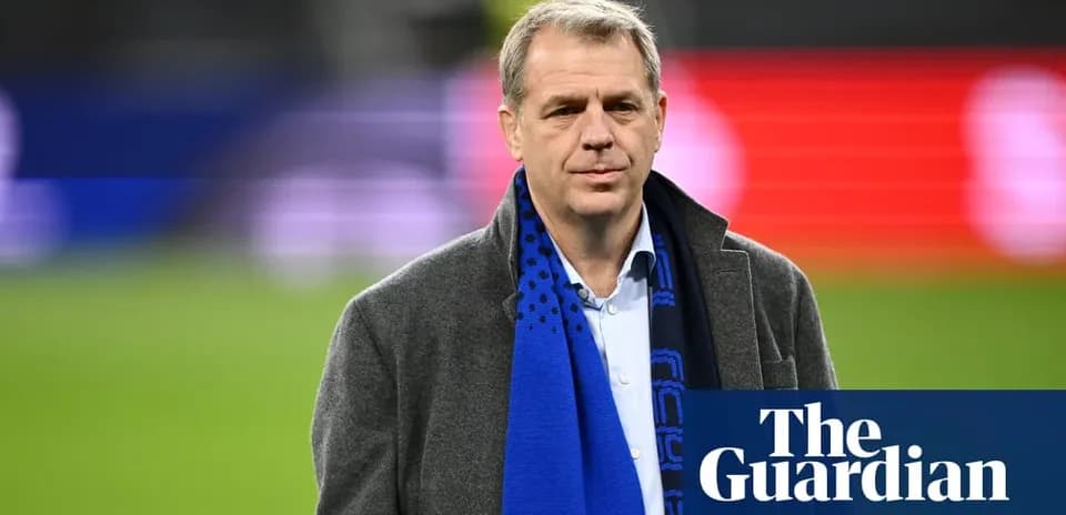 Man in a coat wearing a blue scarf on field