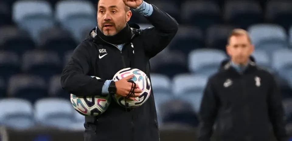 Coach instructing players while holding footballs