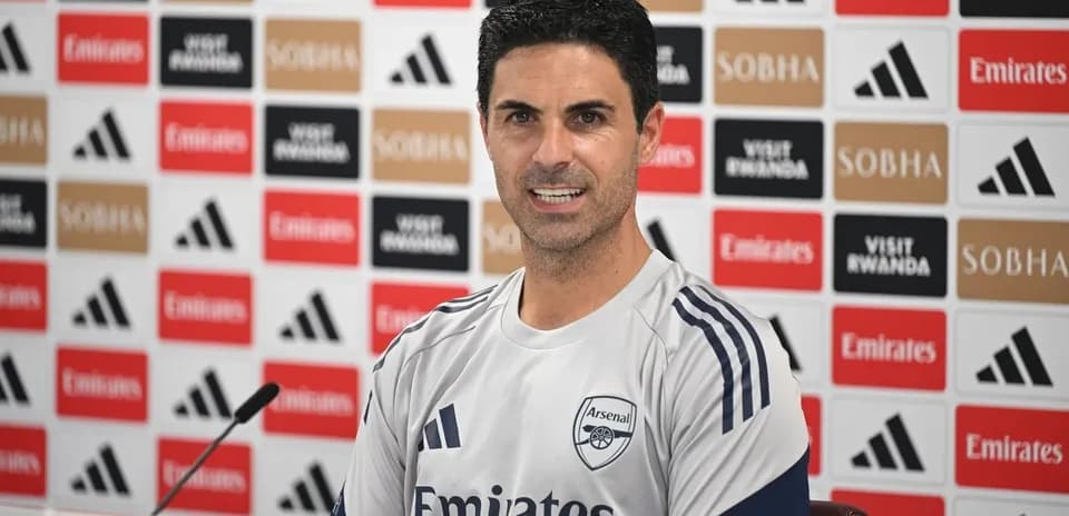 Manager speaking at press conference with Arsenal logo