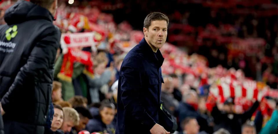 Coach observing fans holding team scarves in stadium