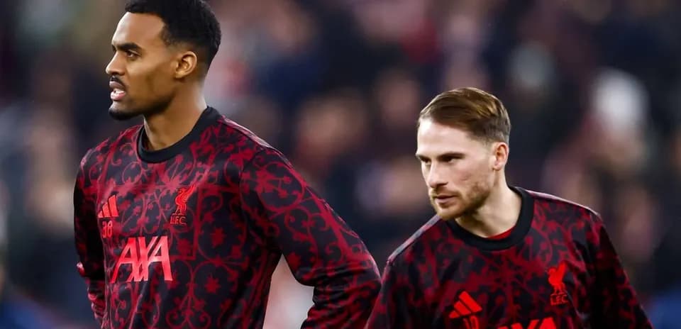 Two Liverpool players in warm-up jerseys on pitch