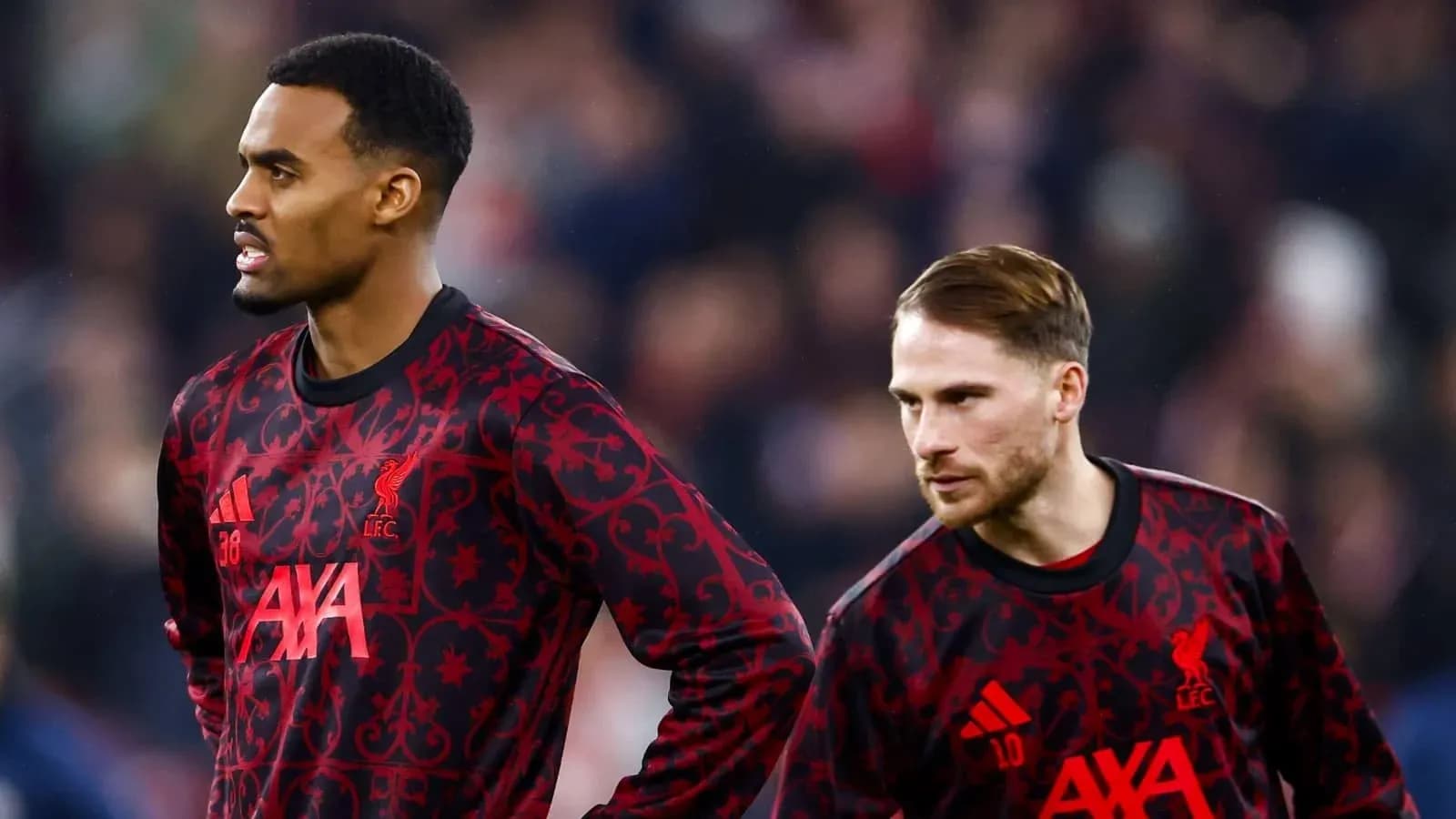 Two Liverpool players in warm-up jerseys on pitch