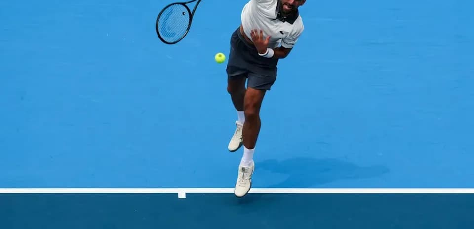 Player serving during a tennis match on blue court