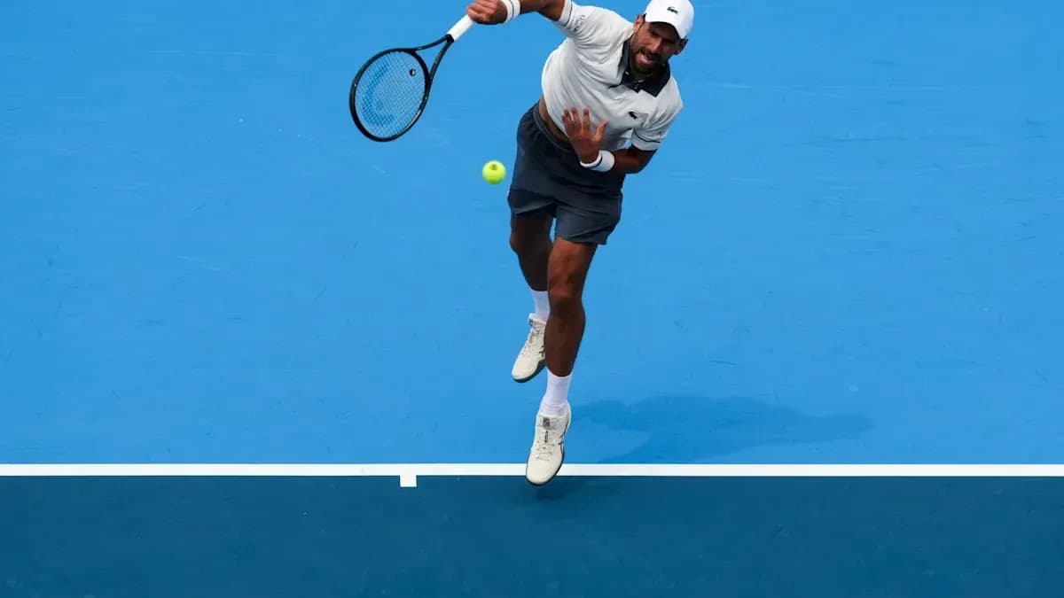 Player serving during a tennis match on blue court