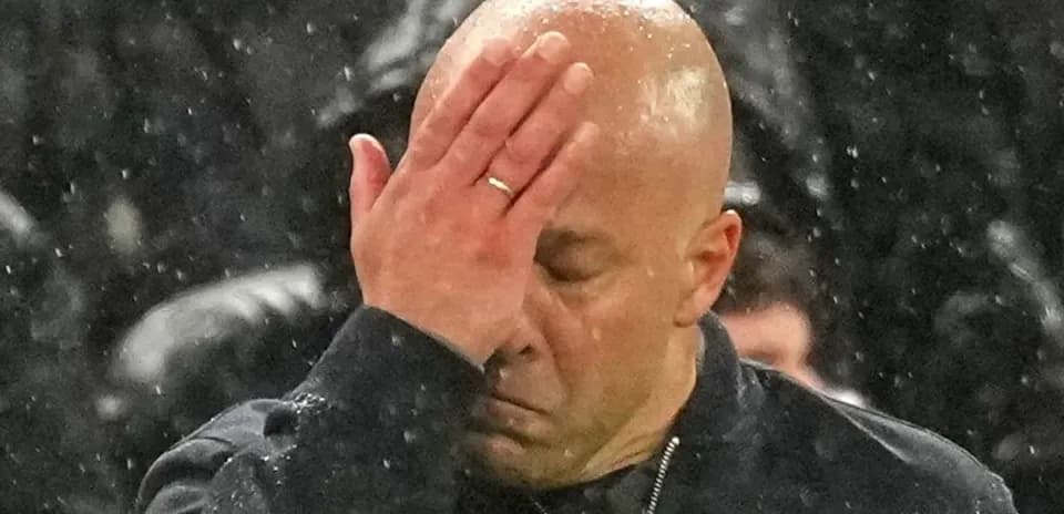 Coach with hand on forehead in rain