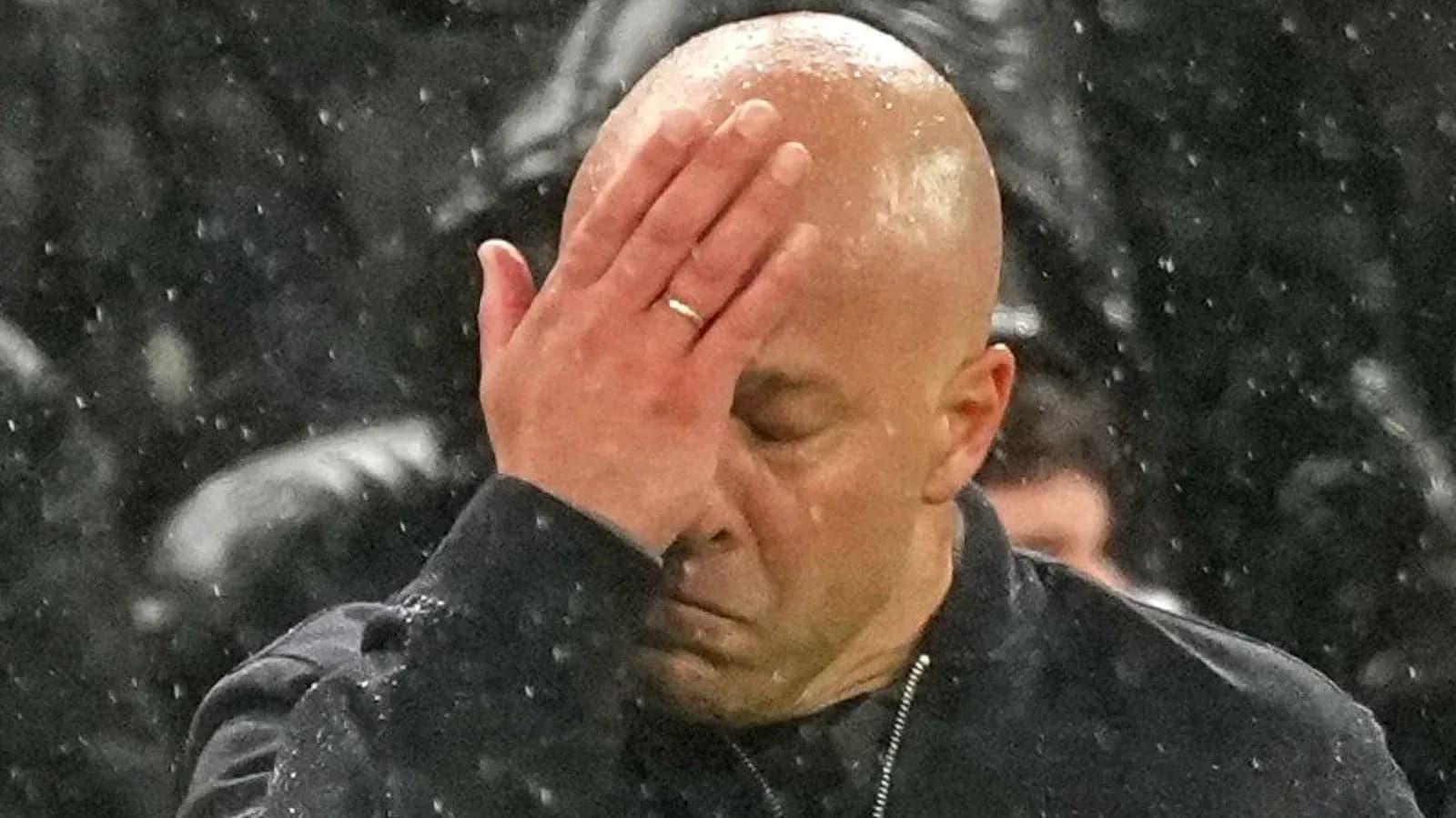 Coach with hand on forehead in rain