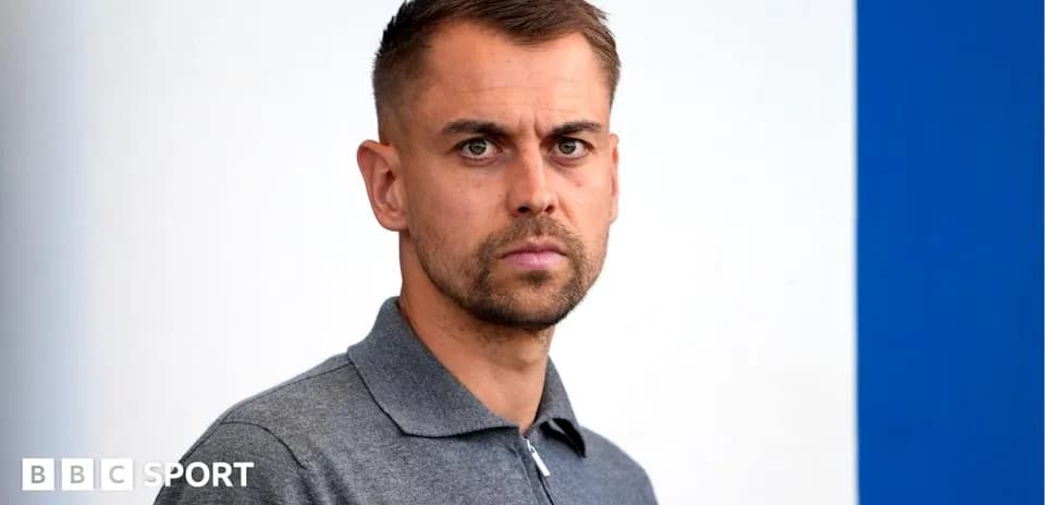 Man in gray shirt posing against a blue background