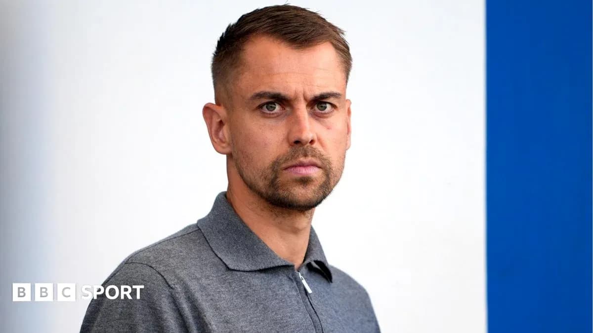 Man in gray shirt posing against a blue background