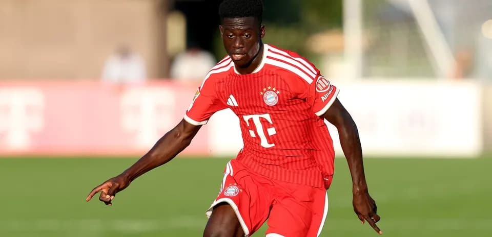 Player dribbling on the field in Bayern Munich kit