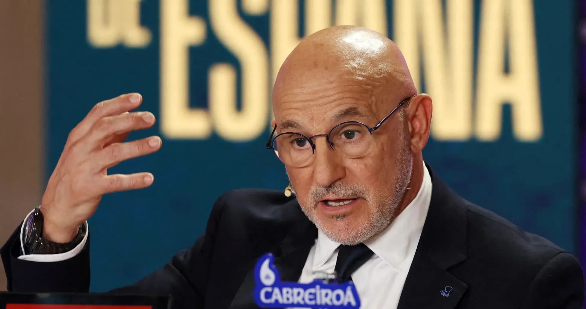 Man speaking at a press conference with logos