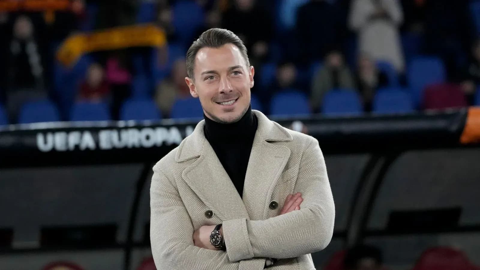 Man in stylish coat smiling on sidelines