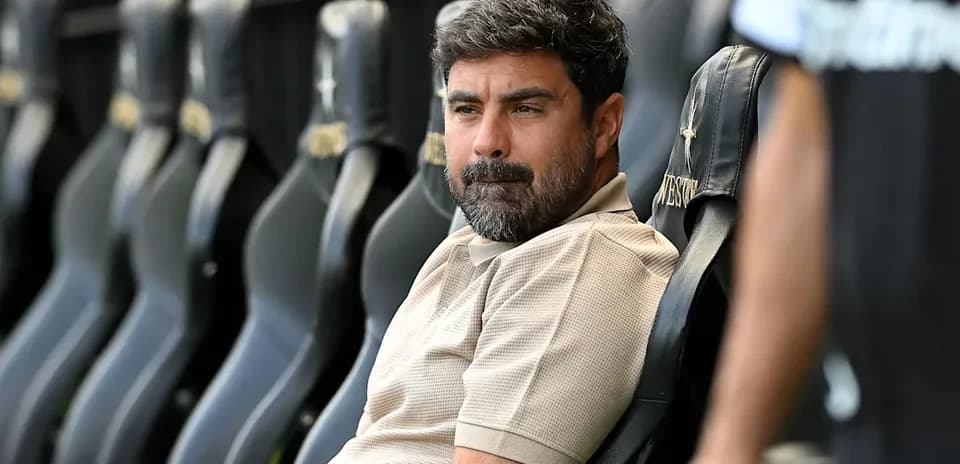 Coach seated on bench during match preparation