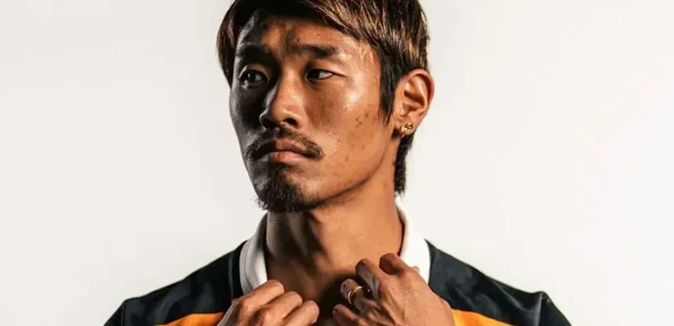 Athlete posing in sports jersey against plain background