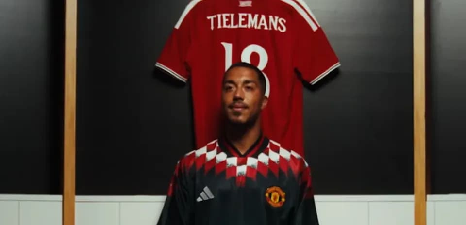 Player posing in Manchester United jersey with red shirt behind