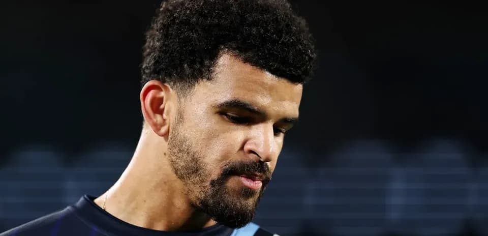 Player in training jersey looking down thoughtfully