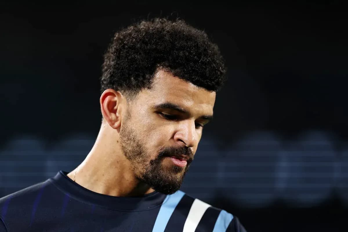Player in training jersey looking down thoughtfully