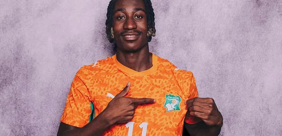 Player in orange jersey pointing at team logo