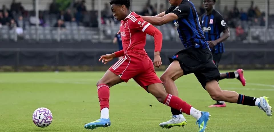 Player in red shirt dribbling past defender in blue