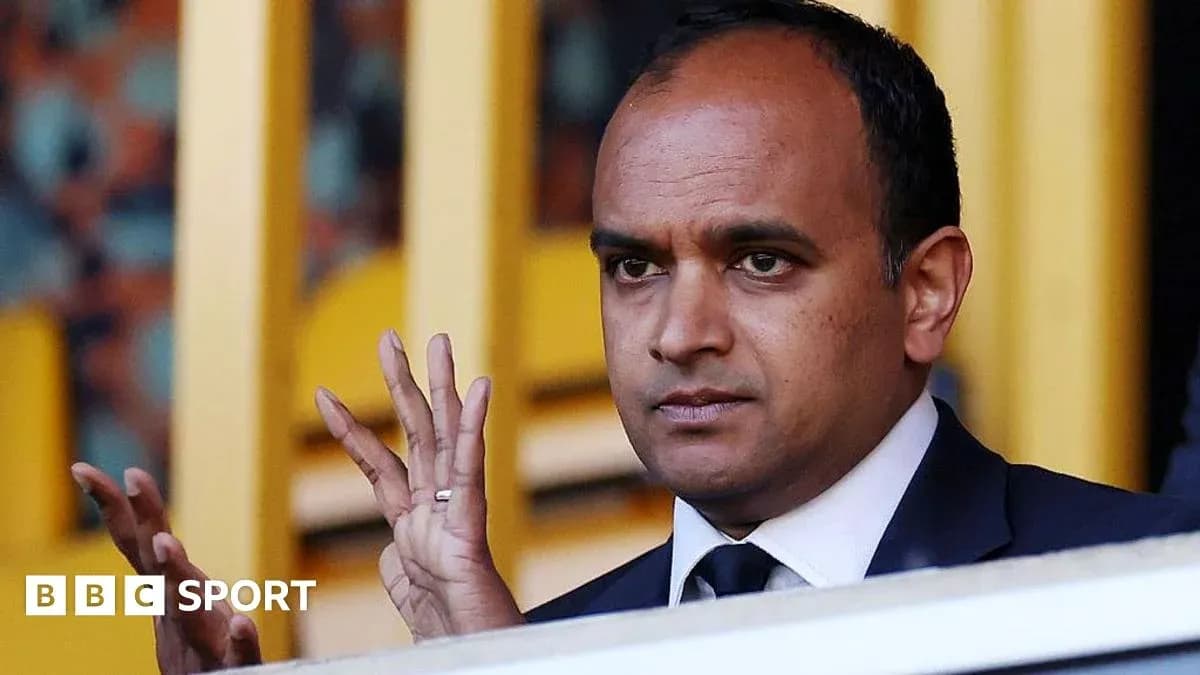 Man gesturing in a sports venue box