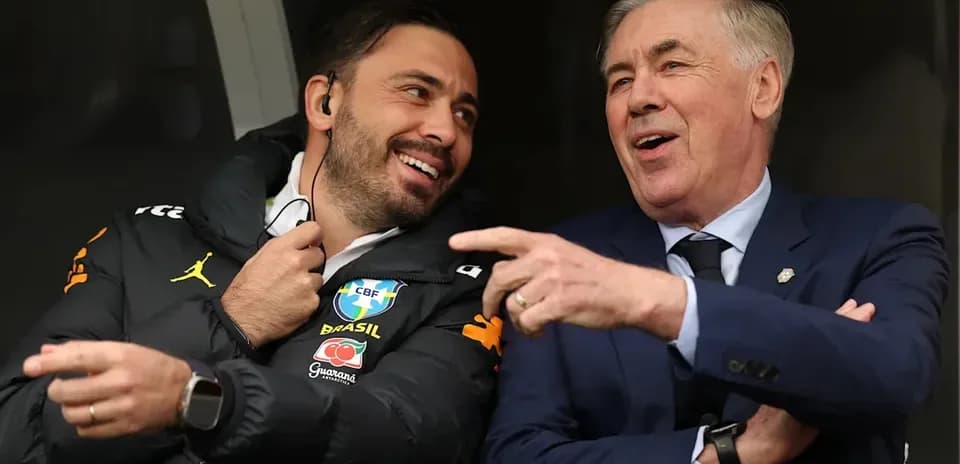 Two coaches laughing in a sports bench area