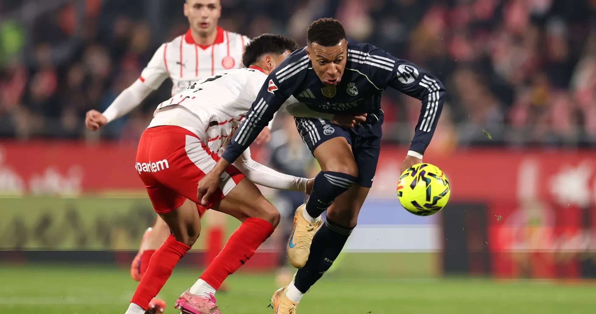 Real Madrid player dribbling past Girona opponent