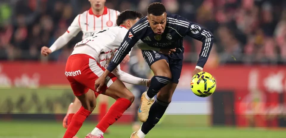 Real Madrid player dribbling past Girona opponent